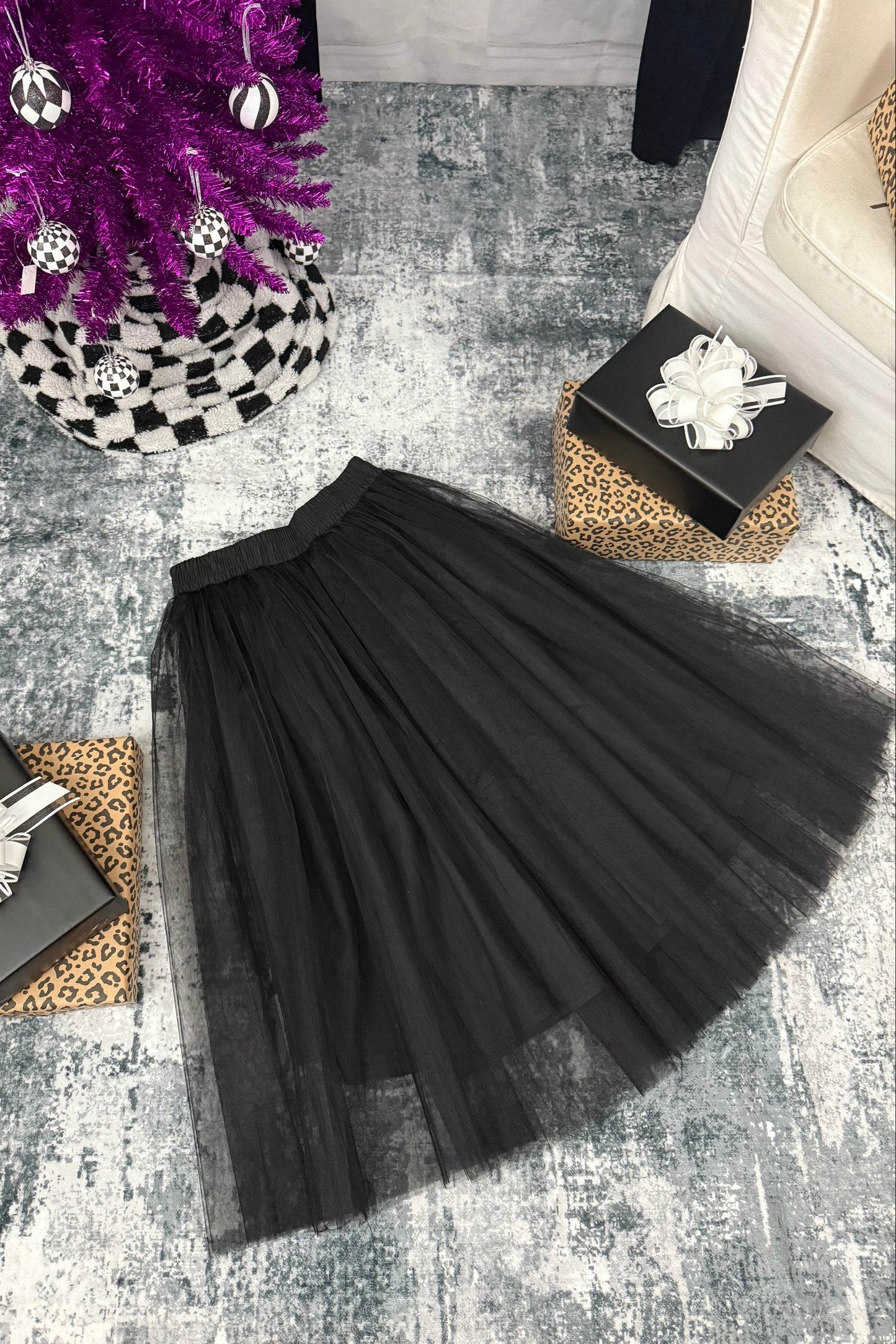 Black pleated skirt on a textured surface with decorative items around