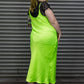 Woman wearing a bright green slip dress with black lace details against a metal shutter background.