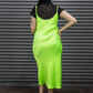 Person wearing a bright green slip dress with a black leopard print top against a metallic shutter background.