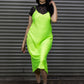 Woman wearing a bright green dress with black sleeves against a metallic shutter background