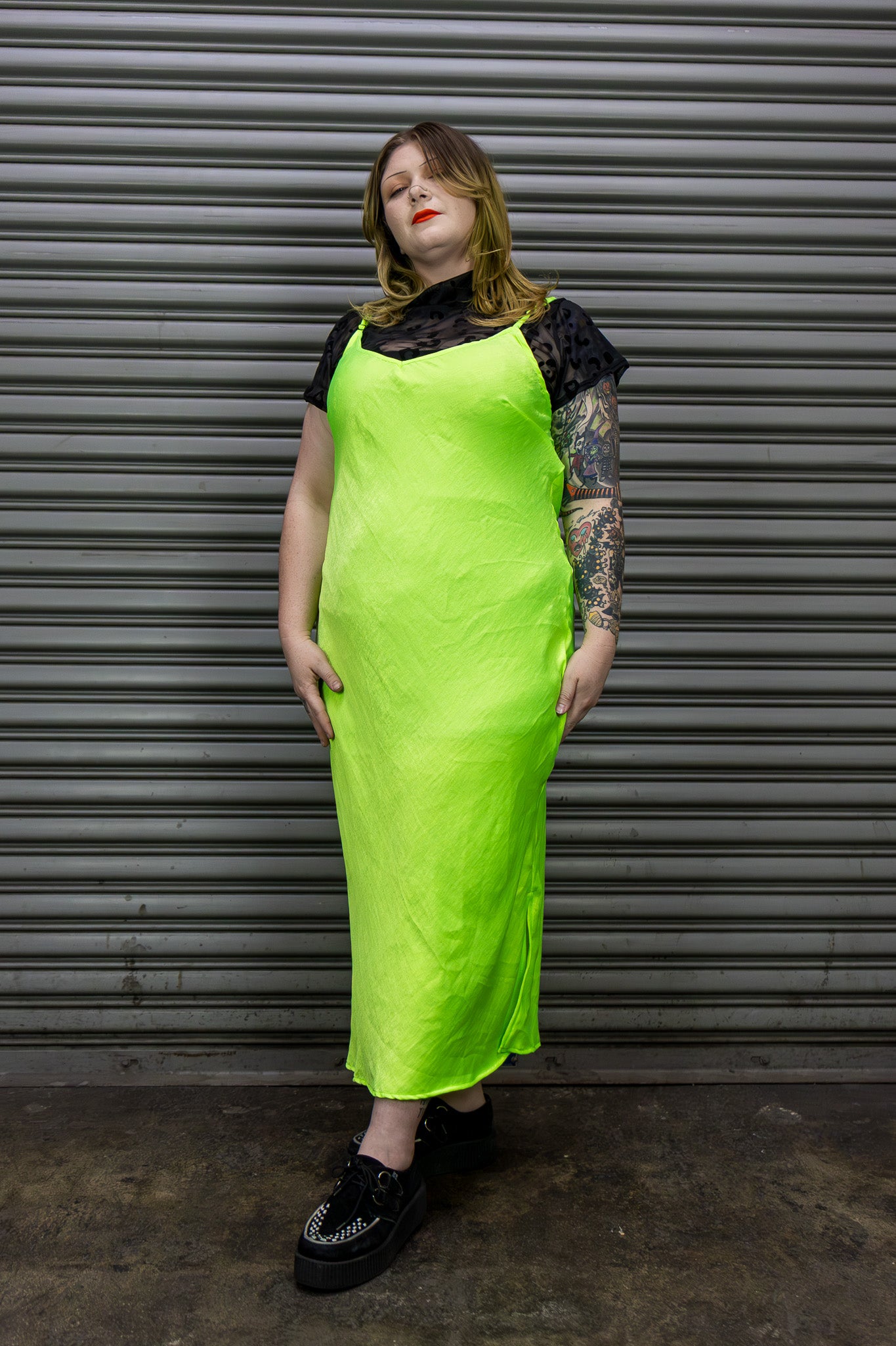 Person wearing a bright green dress against a metallic shutter background