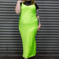 Person wearing a bright green dress with black lace top against a metallic shutter background