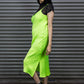 Person wearing a bright green dress with black lace details against a metallic shutter background