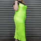 Person wearing a bright green dress standing in front of a metallic shutter.