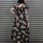 Person wearing a floral dress standing in front of a metallic shutter.