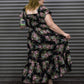 Woman wearing a floral dress standing against a metallic shutter.