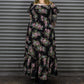 Person wearing a floral dress standing in front of a metal shutter.
