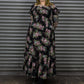 Person wearing a floral dress standing in front of a metallic shutter.