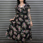 Woman wearing a floral dress standing in front of a metal shutter.