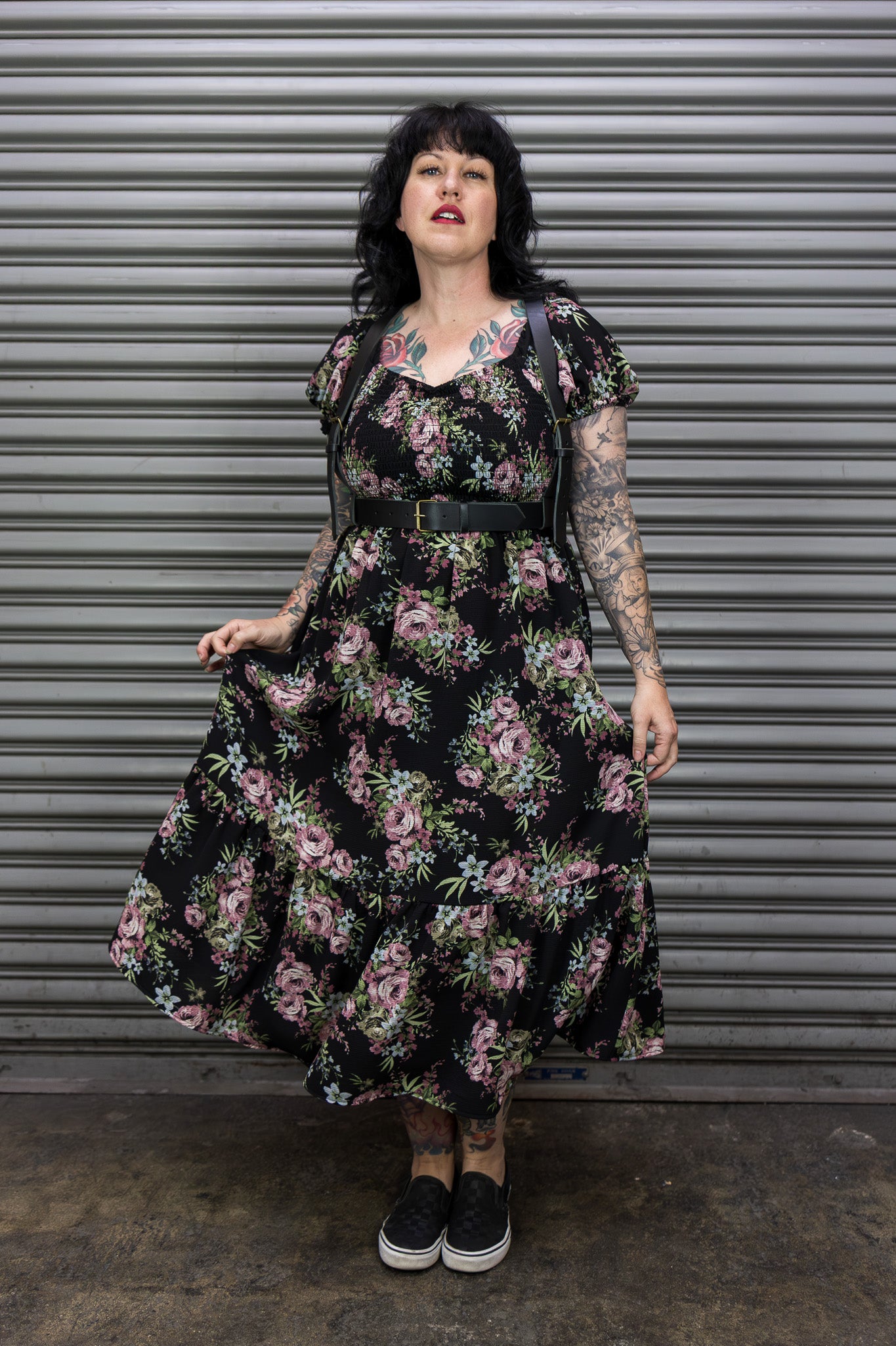 Woman wearing a floral dress standing in front of a metal shutter.