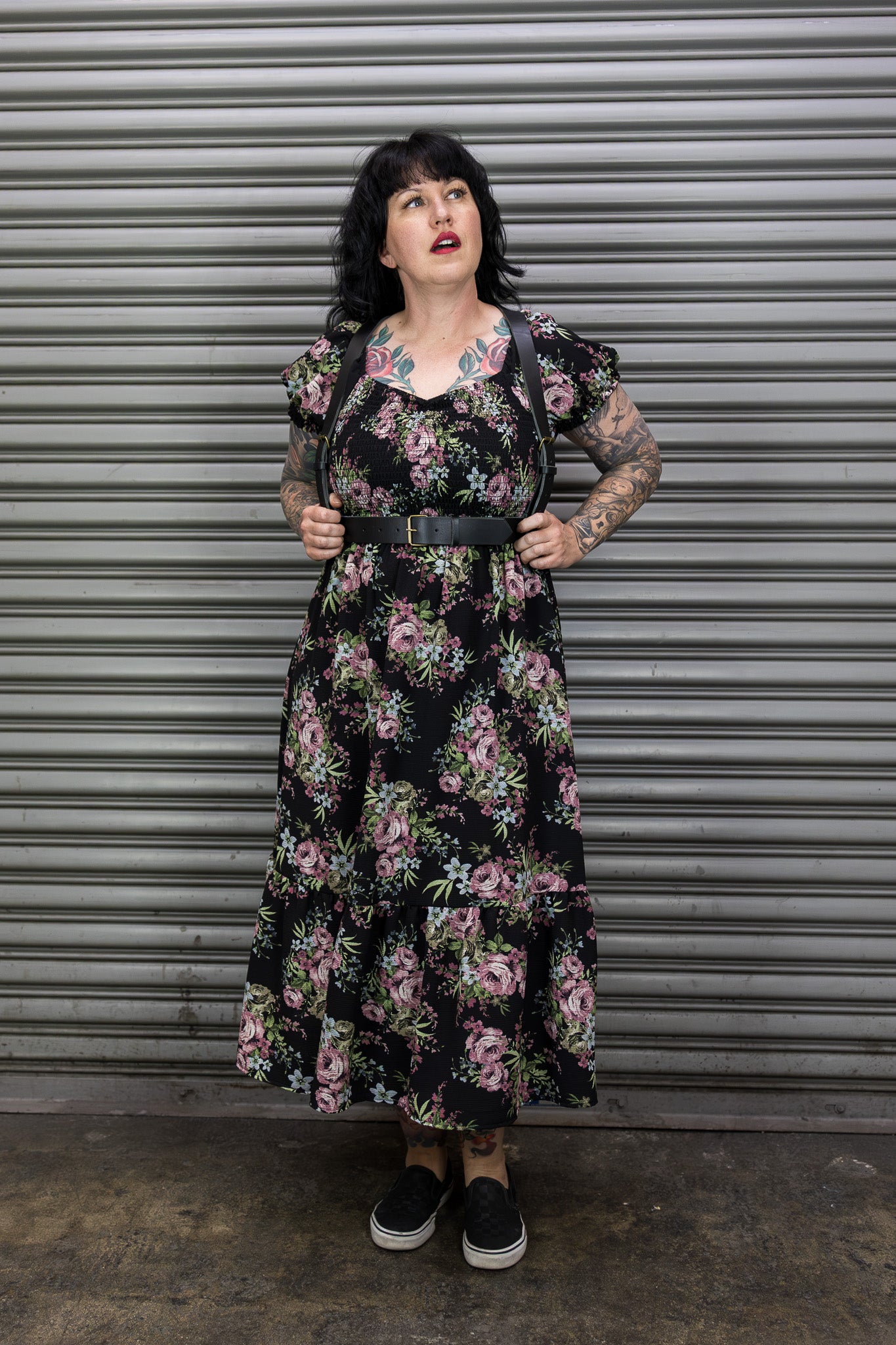 Woman wearing a floral dress standing in front of a metal shutter.