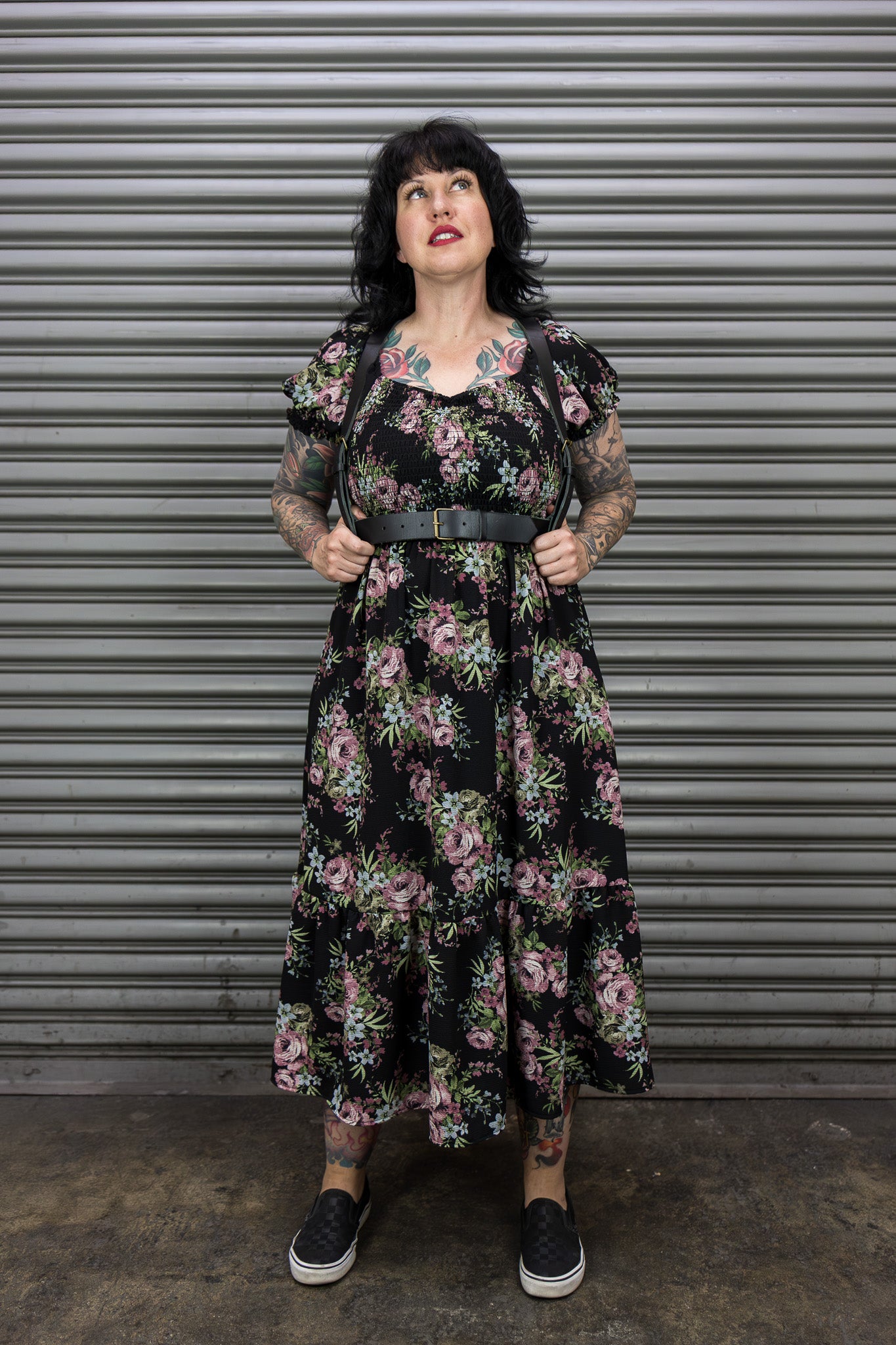 Woman wearing a floral dress standing in front of a metal shutter.
