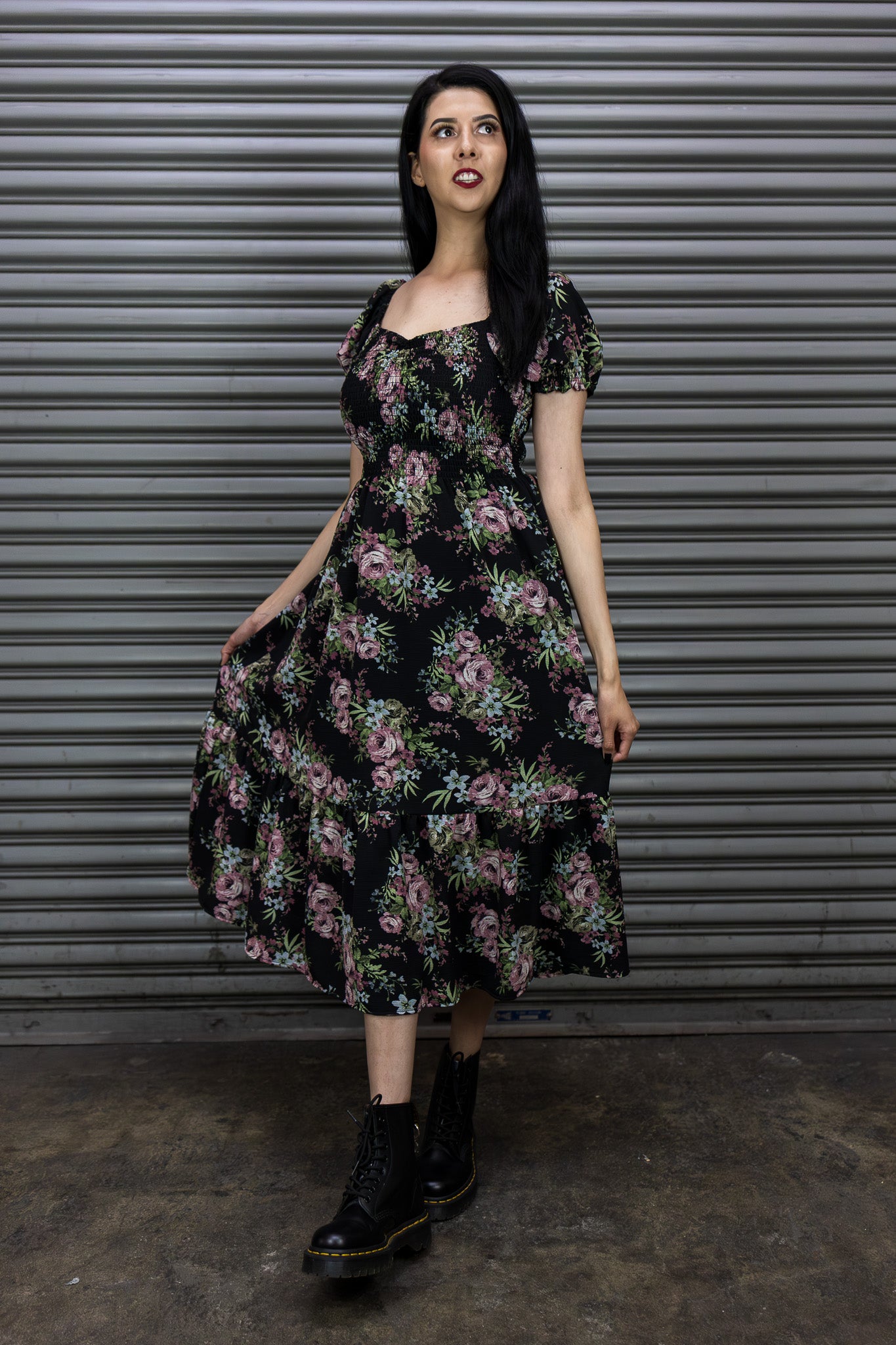 Woman wearing a floral dress standing in front of a metallic shutter.