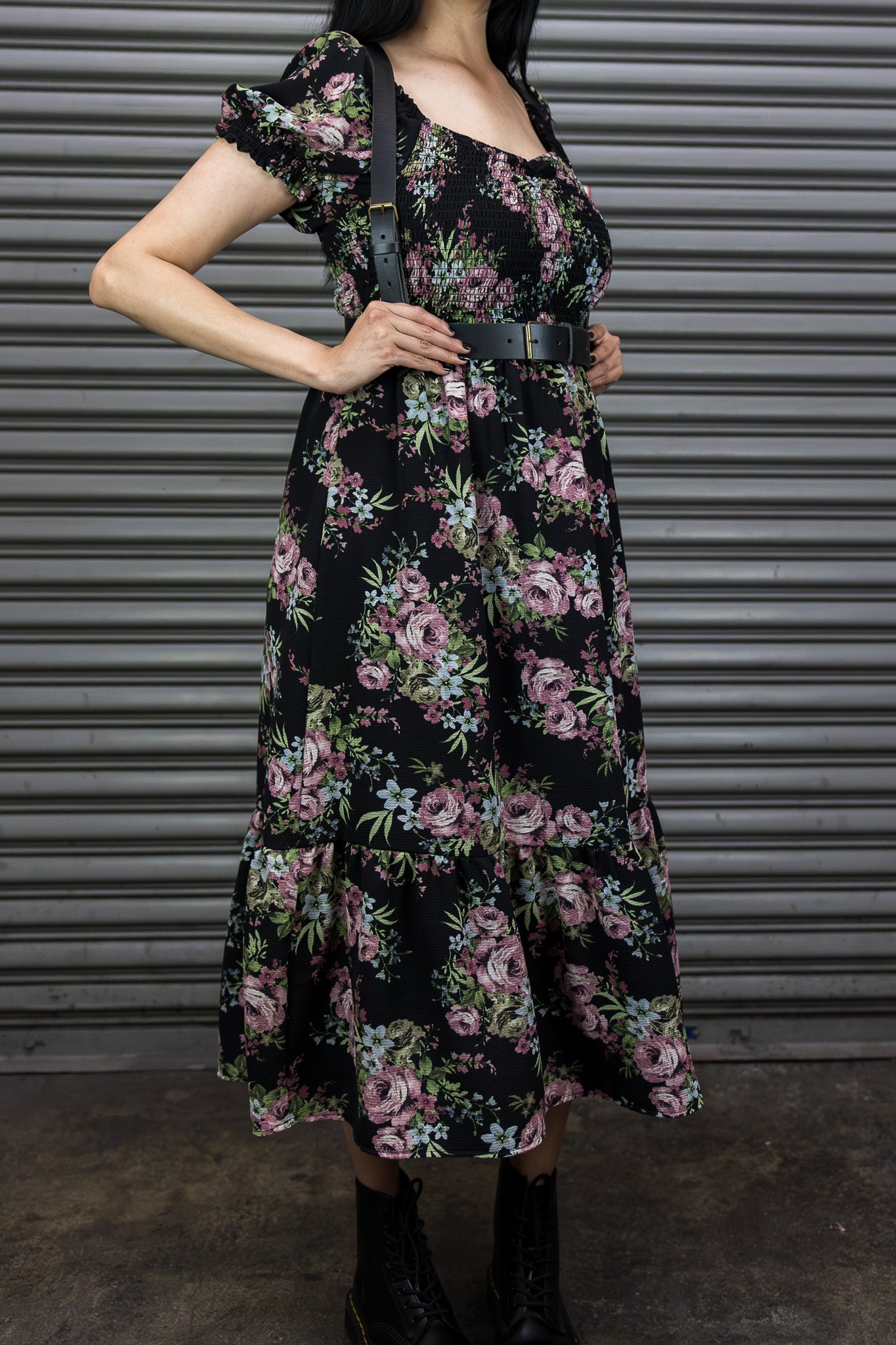Person wearing a floral dress with a belt against a metallic background