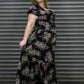 Woman wearing a floral dress standing in front of a metal shutter.