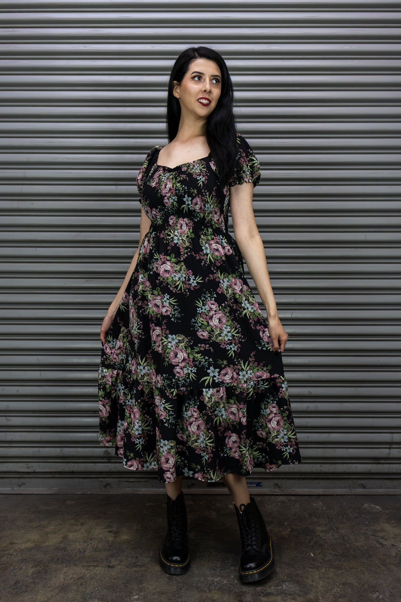 Woman wearing a floral dress standing in front of a metallic shutter.