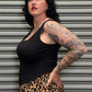 Woman wearing a black tank top and leopard print skirt standing against a metallic shutter.