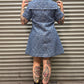 Person wearing a blue leopard print denim dress standing in front of a metal shutter.