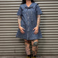 Person wearing a blue leopard print denim dress standing in front of a metal shutter.