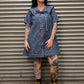 Person wearing a blue denim leopard print dress standing in front of a metal shutter.