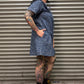Person wearing a blue leopard print denim dress standing in front of a metal shutter.