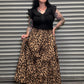 Person wearing a black outfit with a leopard print skirt .